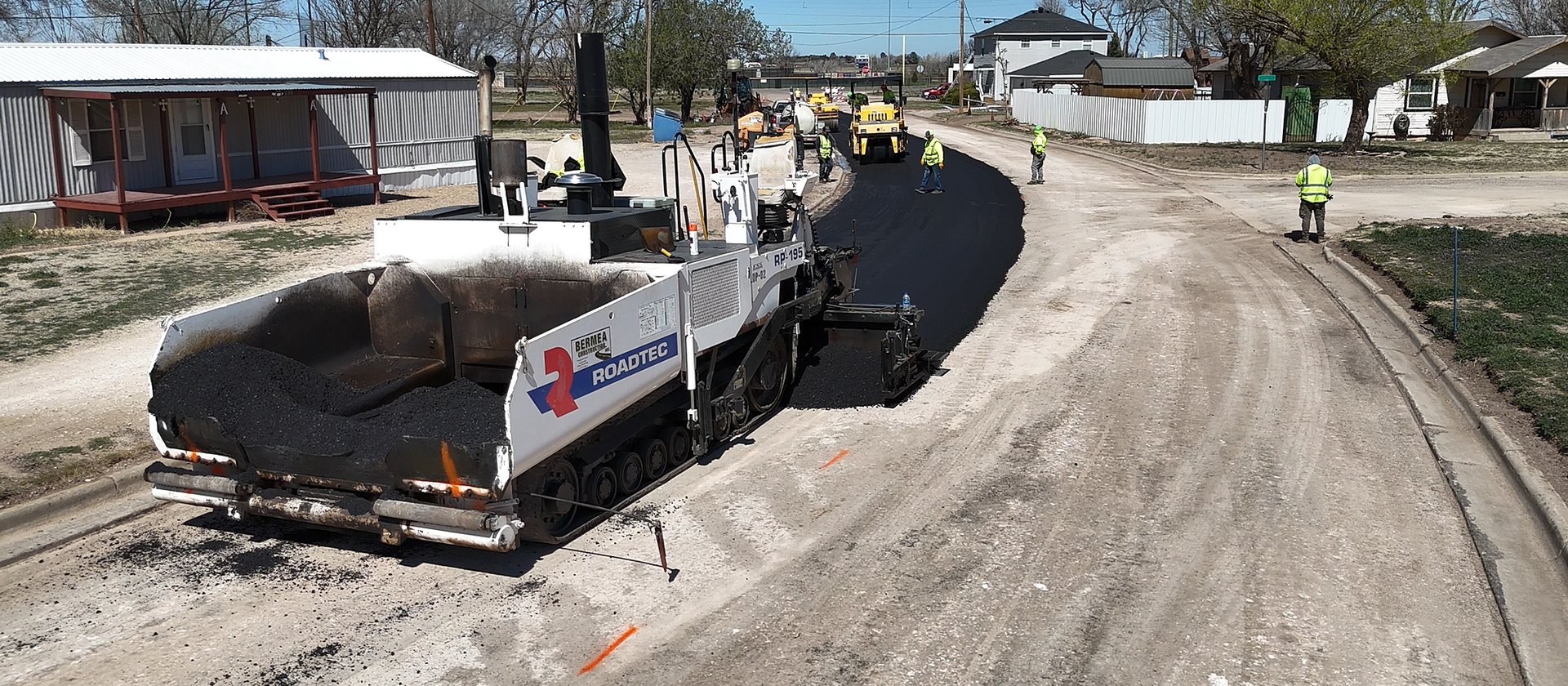 Bermea Construction paver and crew laying a new asphalt mat on a city street