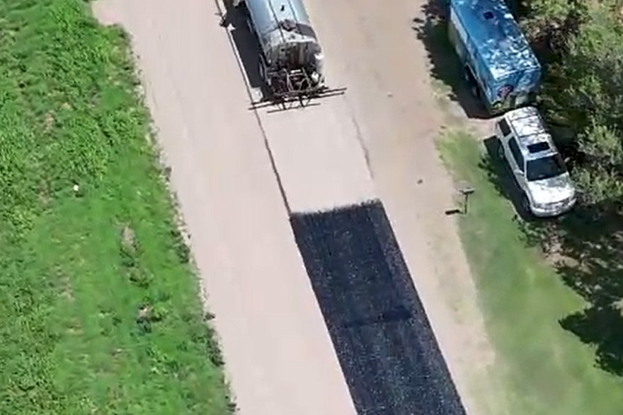 Distributor truck laying asphalt emulsion, with fresh chip seal already down behind it
