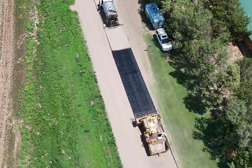 Chip spreader following the distributor, finished surface trailing behind