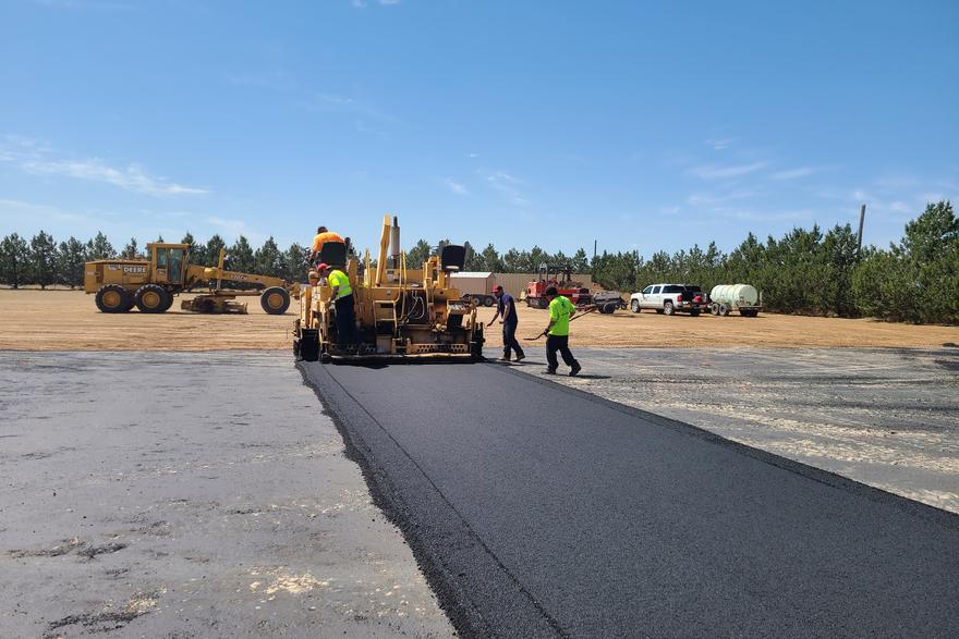 Asphalt paver placing hot mix across a wide area
